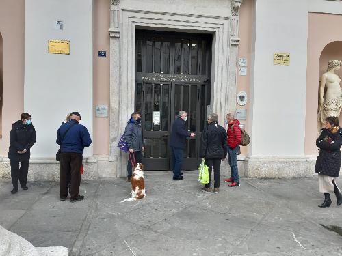 Persone in attesa di accedere allo sportello per i ristori Coop all'esterno della sede camerale di piazza della Borsa a Trieste