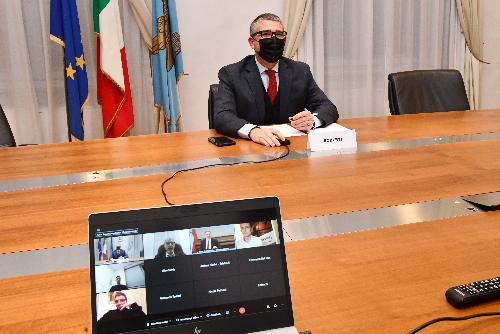 Il governatore Massimiliano Fedriga in videoconferemza sullo schermo assieme ai presidenti delle Province auttonome di Trento e Bolzano, Fugatti e Kompatscher, e l'assessore regionale Pierpaolo Roberti in presenza 