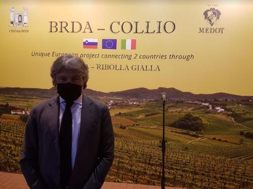 L'assessore Bini davanti il grande manifesto che promuove la regione transfrontaliera del Brda-Collio