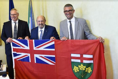 L'assessore Roberti, il ministro Tibollo e il presidente del Consiglio regionale Bordin con la bandiera dell'Ontario.