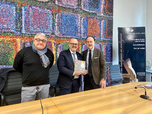 Il presidente della Scuola mosaicisti del Friuli Stefano Lovison (primo a destra) consegna all'assessore regionale Sebastiano Callari un libro sull'istituto spilimbergjhese