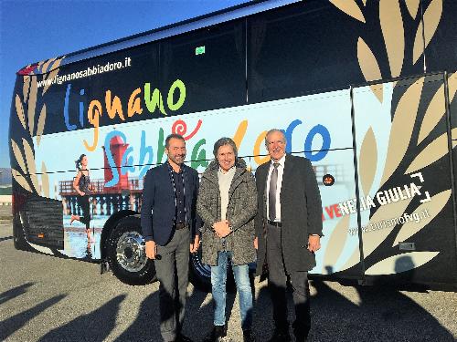 L'assessore regionale al Turismo Sergio Emidio Bini con il direttore di PromoTurismoFvg Lucio Gomiero e l'assessore di Lignano Massimo Brini davanti al nuovo pullman dell'Udinese Calcio con la gigantografia della località balneare