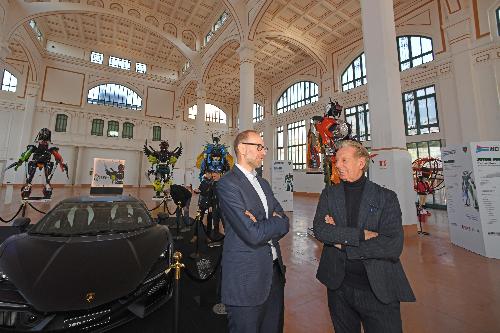 Scoccimarro e Andriolo davanti alla Lamborghini in esposizione per l'apertura della mostra accanto ai sei robot realizzati con scarti di lavorazione 