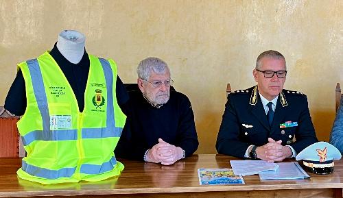 Il gilet che sarà indossato dai volontari per la sicurezza del Comune di Muggia e a destra il comandante della Polizia locale Roberto Dellosto.